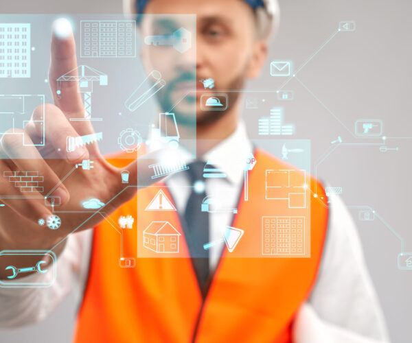 Close up of architect wearing reflective vest and helmet. Selective focus of digital tactile charts screen, man touching virtual icon on projection. Concept of digitalization, construction.